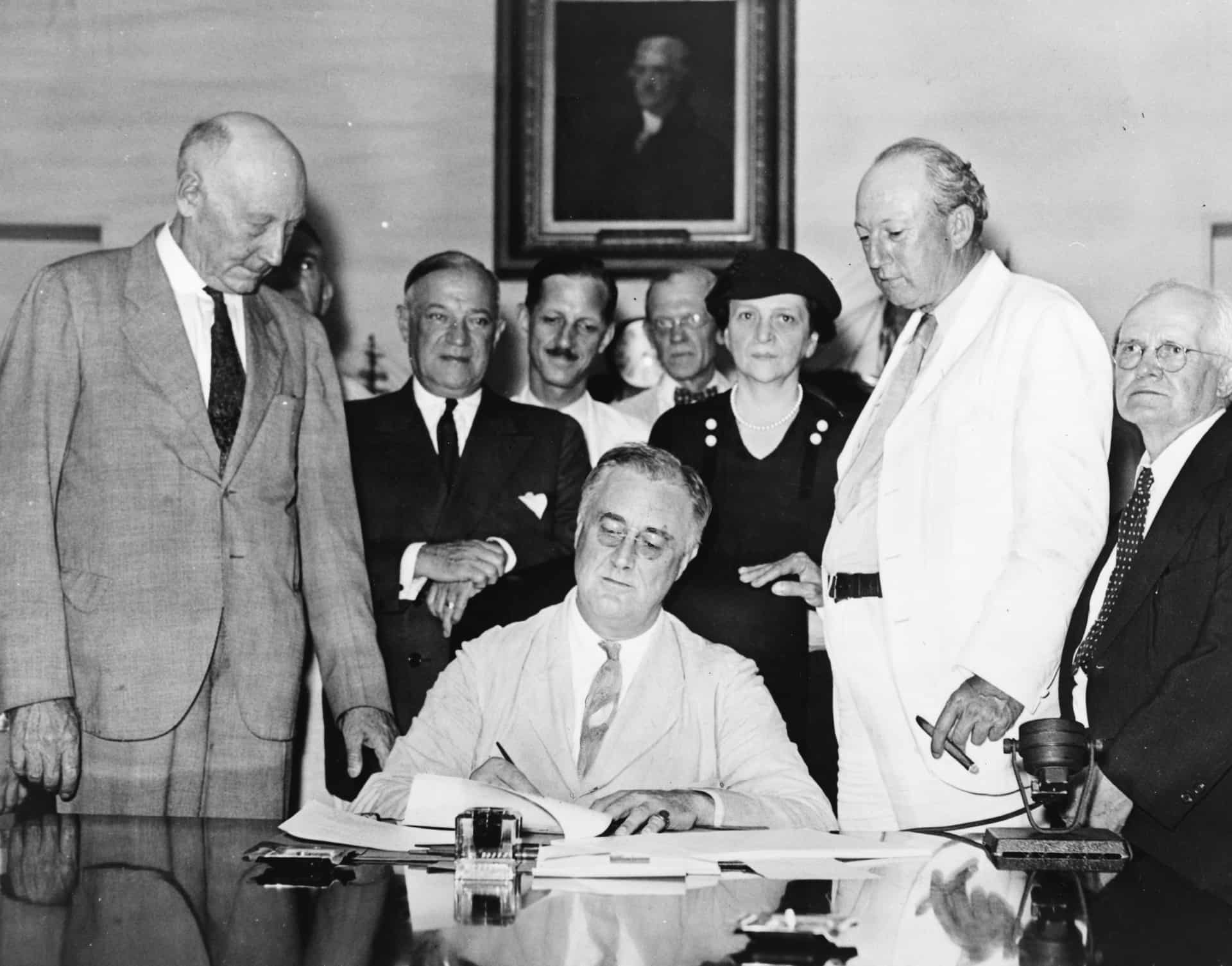 Roosevelt signs the Social Security Act into law, August 14, 1935. © Public domain